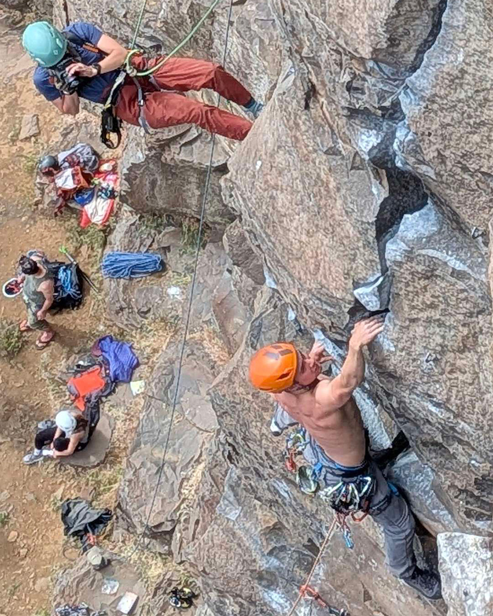 Rock climbing photographer paused in a hands free rappel set up with her camera out